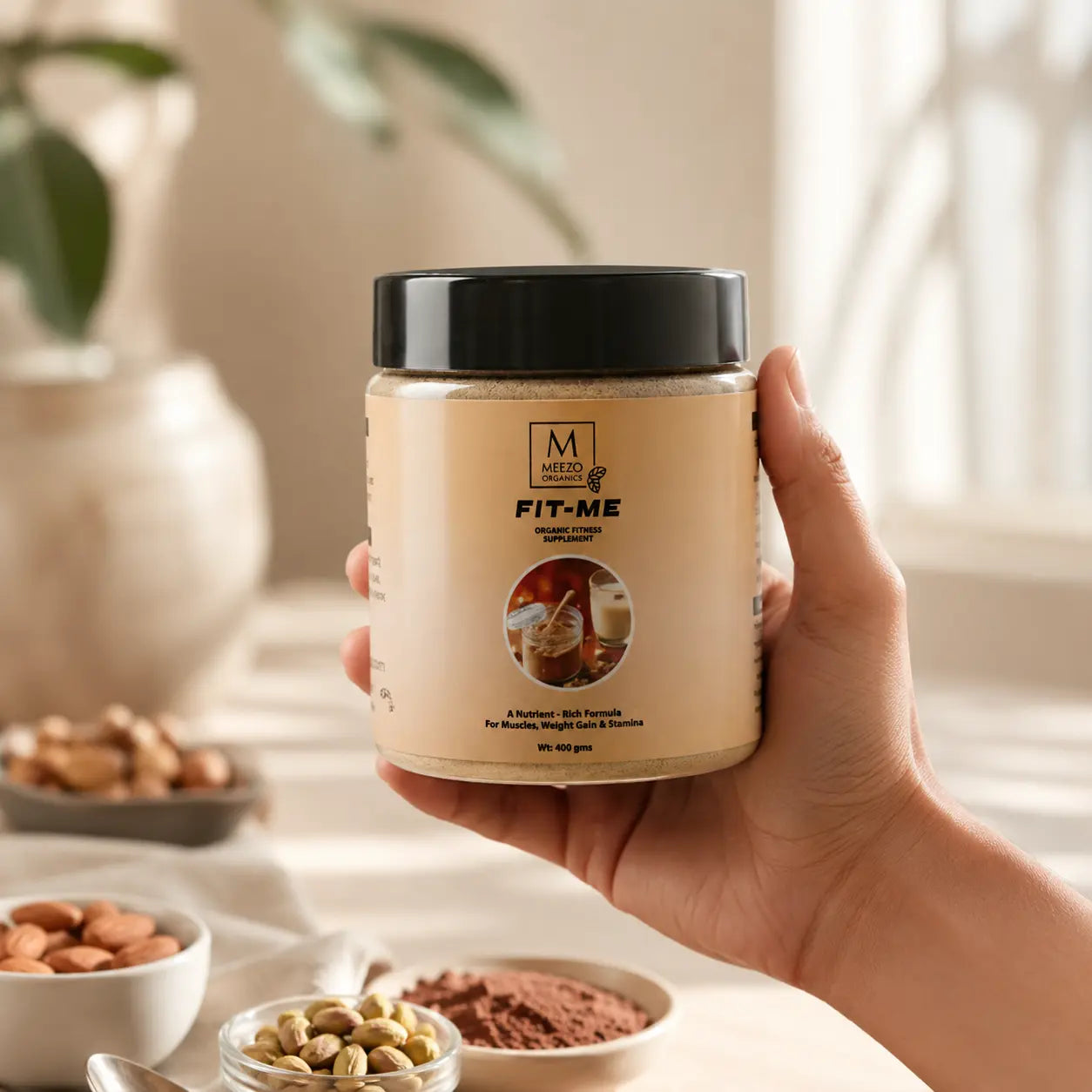 Hand holding a jar labeled 'Fit-Me' with bowls of nuts and powder in the background.