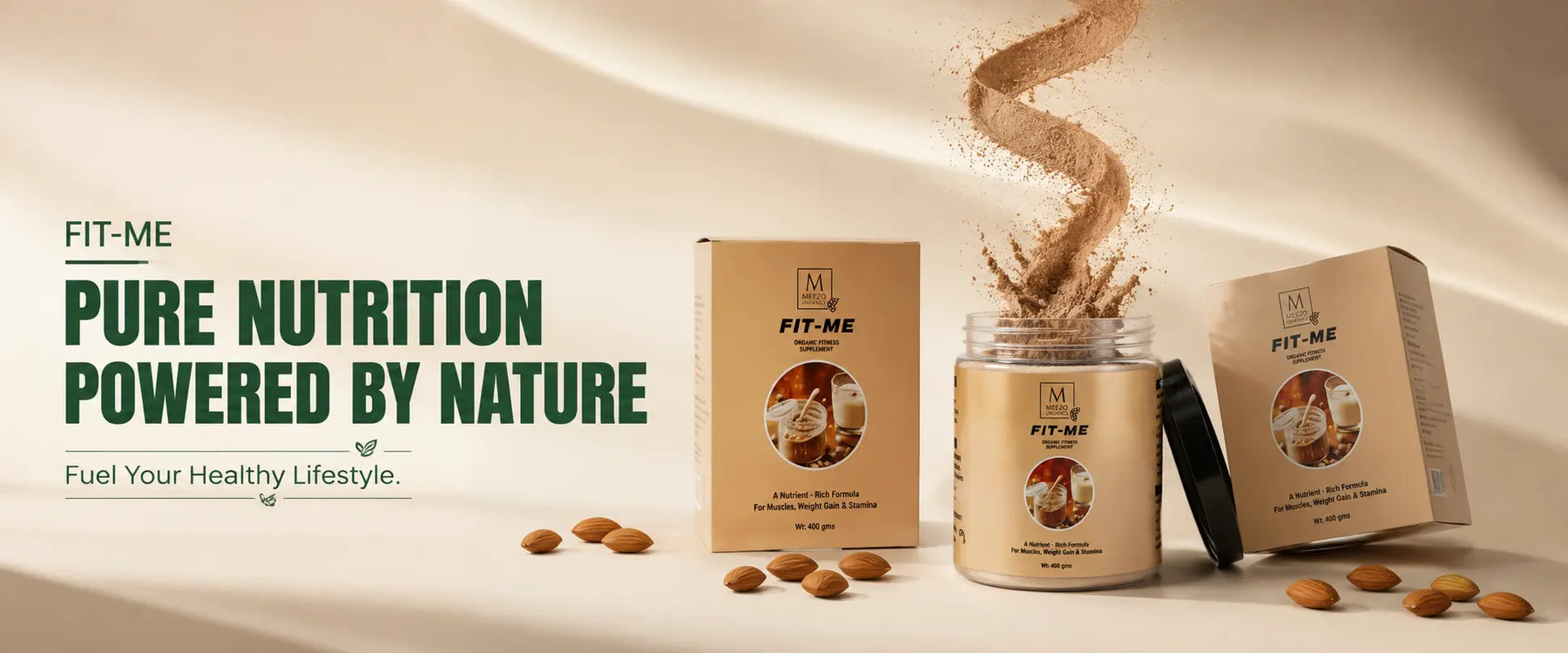 FIT-ME Pure Nutrition powder shown in a beige jar with its matching kraft-style box and lid on a draped beige background, with scattered almonds and a dramatic powder splash effect. Large text on the left reads 'FIT-ME PURE NUTRITION POWERED BY NATURE.